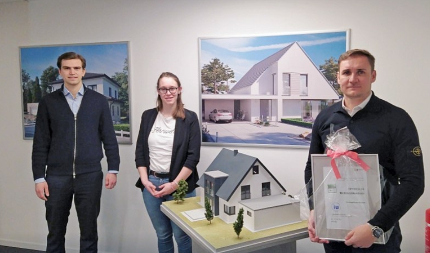 Das Bild zeigt Geschäftsführer Siegfried Boldt (rechts), eine Vertreterin der IU Internationale Hochschule (mitte), sowie den dualen Studenten Mateo Roso (links) in den Räumlichkeiten der Concept Haus GmbH